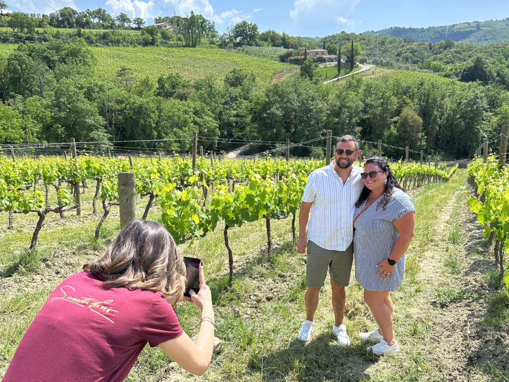 Guests on a Brunello di Montalcino vineyard tour in northern Montalcino, exploring rows of Sangiovese vines before a DOCG wine tasting