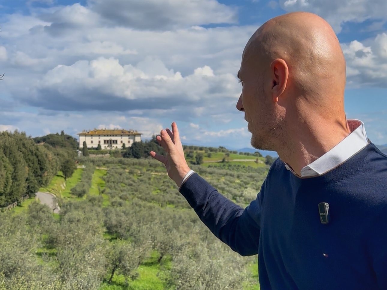 Gabriele guiding a March tour in Carmignano, pointing across olive groves toward the Medici Villa La Ferdinanda (Artimino)