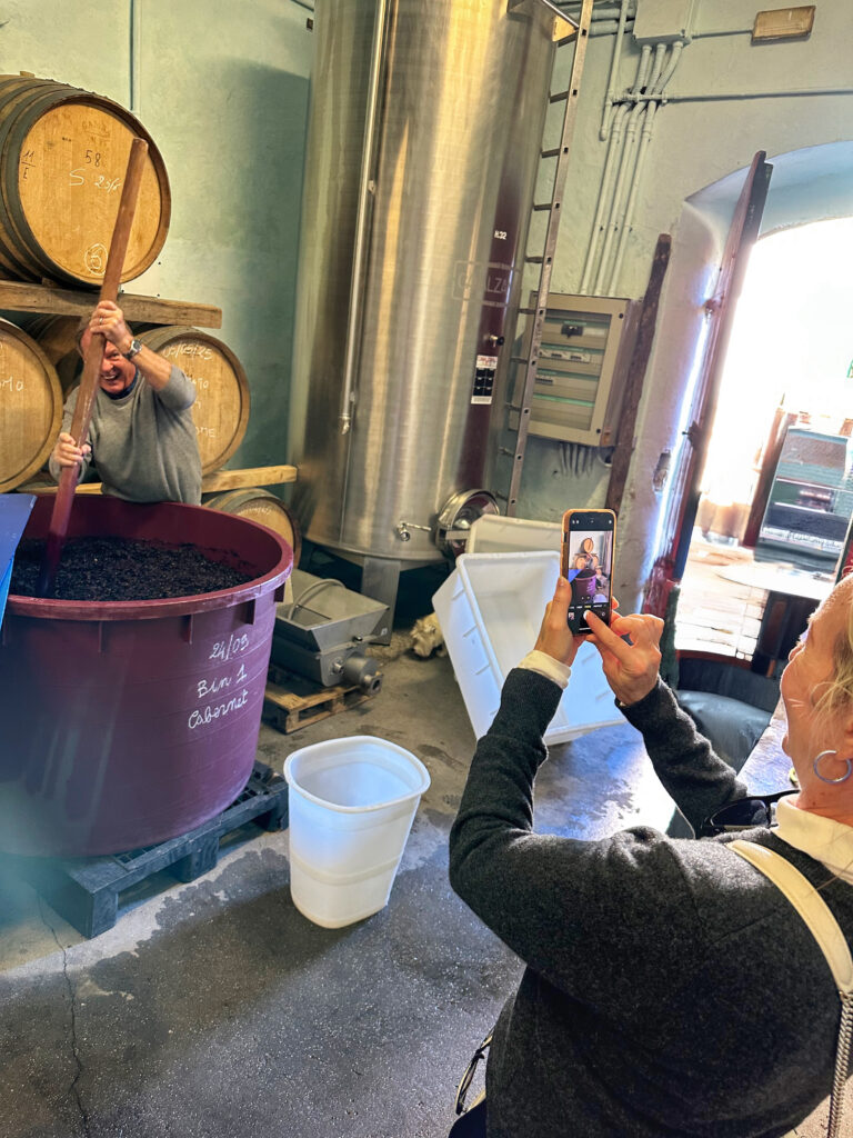 Couple doing manual punch-downs (“follature”) with winemaker Rossella in a Carmignano cellar during the October harvest