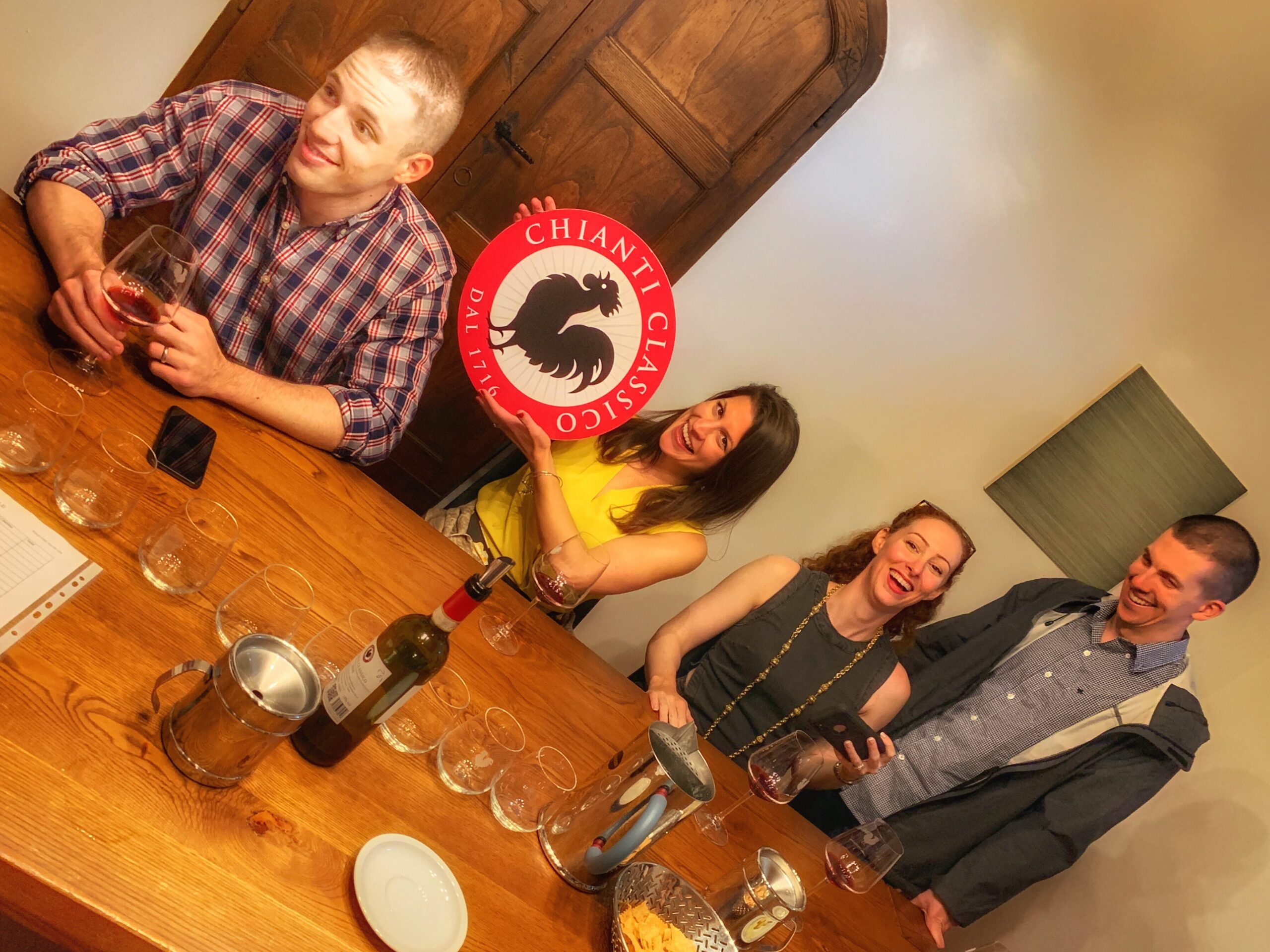 Guests on a Tuscany Uncorked winery tour from Florence posing with the Chianti Classico Black Rooster logo in a Tuscan vineyard