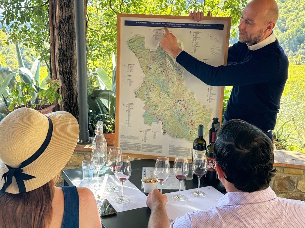 Gabriele Alessandroni explaining the Chianti Classico UGA map to guests during a guided tasting, comparing soils and elevations on a vineyard terrace in Tuscany.