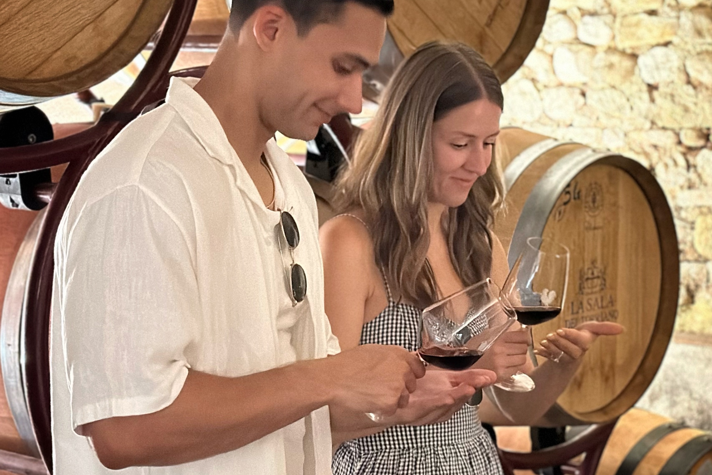 Two guests examining a glass of Chianti Classico during a barrel tasting in a winery cellar on a wine tour from Florence.