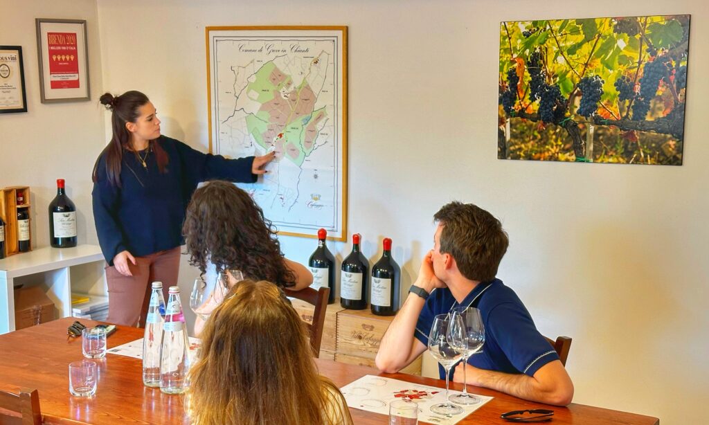 Winery host explaining a Chianti Classico map to guests during an educational wine tasting in Tuscany, showing how a well-planned Tuscany wine tour is built around the right winery choices.
