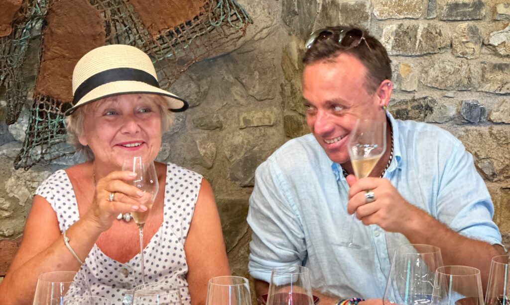 Two guests enjoying a relaxed wine tasting at a Tuscan winery, illustrating the pace and enjoyment of a proper full-day wine tour in Tuscany.