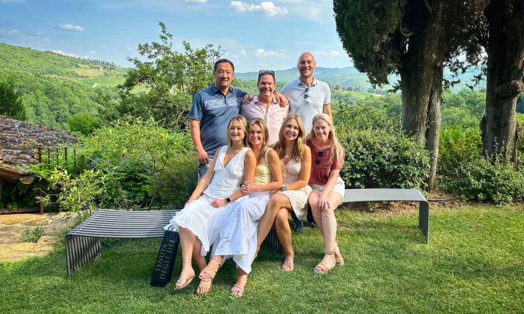 Small group of travelers enjoying a relaxed Tuscany wine tour with vineyard views, showing why fewer winery visits can create a better experience.